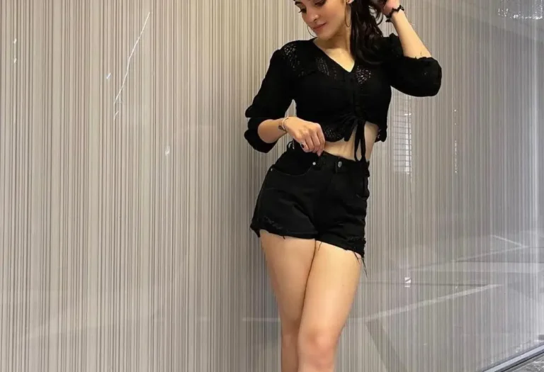 Indian Call Girls in Downtown waring black and stading in fornt of wall